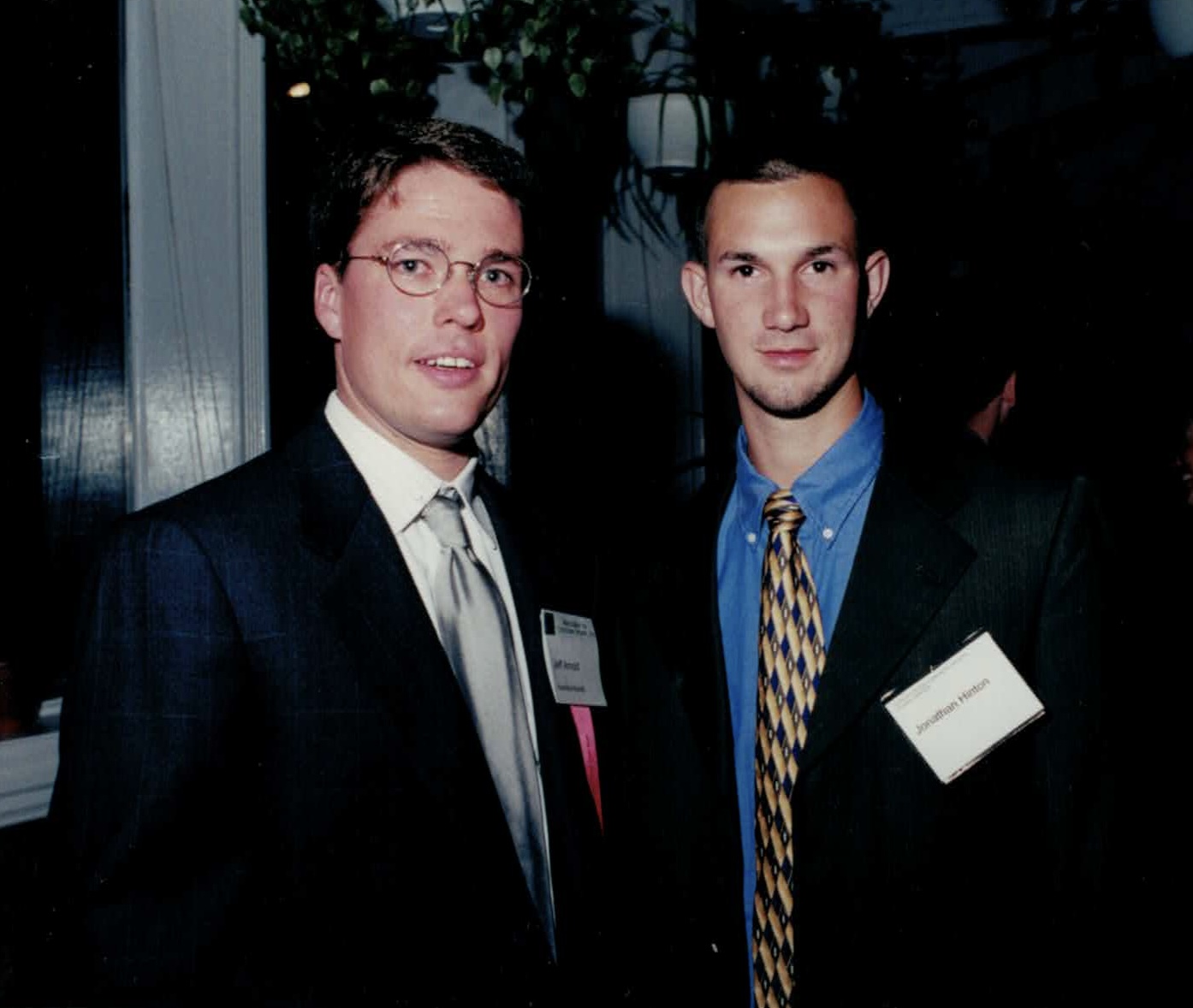 A young Jonathan Hinton in a suit and name badge at a business event